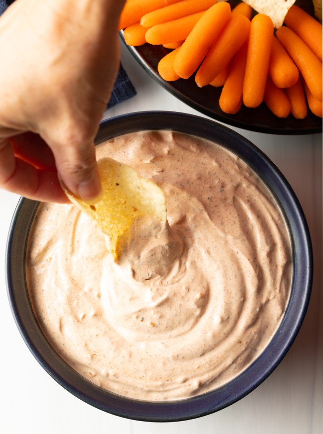 hand with tortilla chip scooping creamy dip made with 3 ingredients