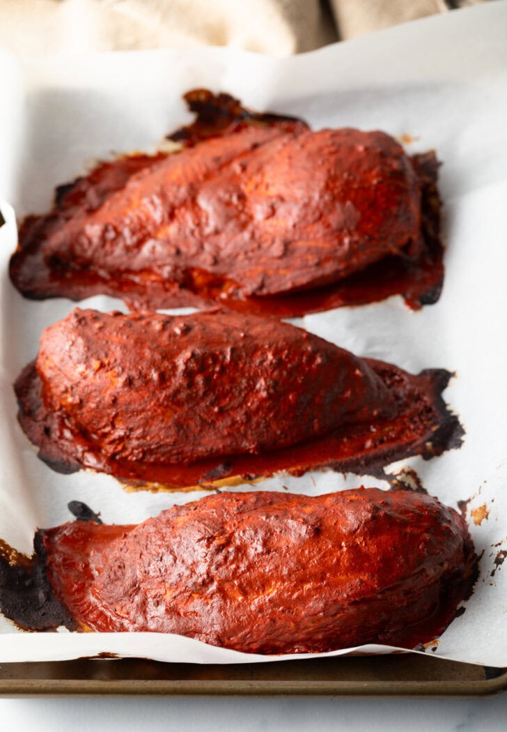 Top down view 3 cooked achiote chicken breasts.