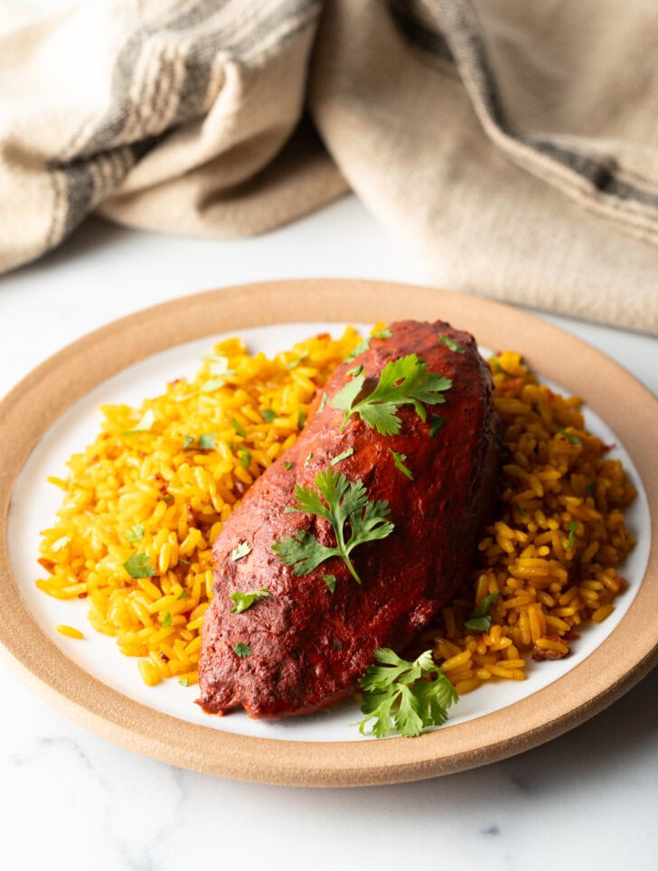 A plate of yellow rice and pollo en achiote chicken breast.