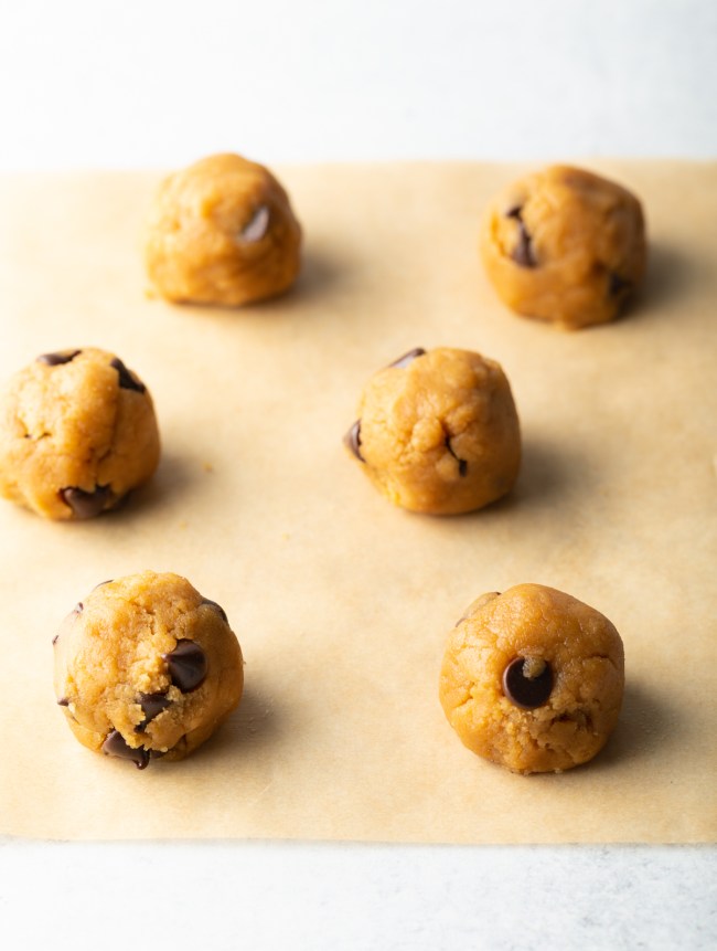 Round balls of cookie dough on parchment.