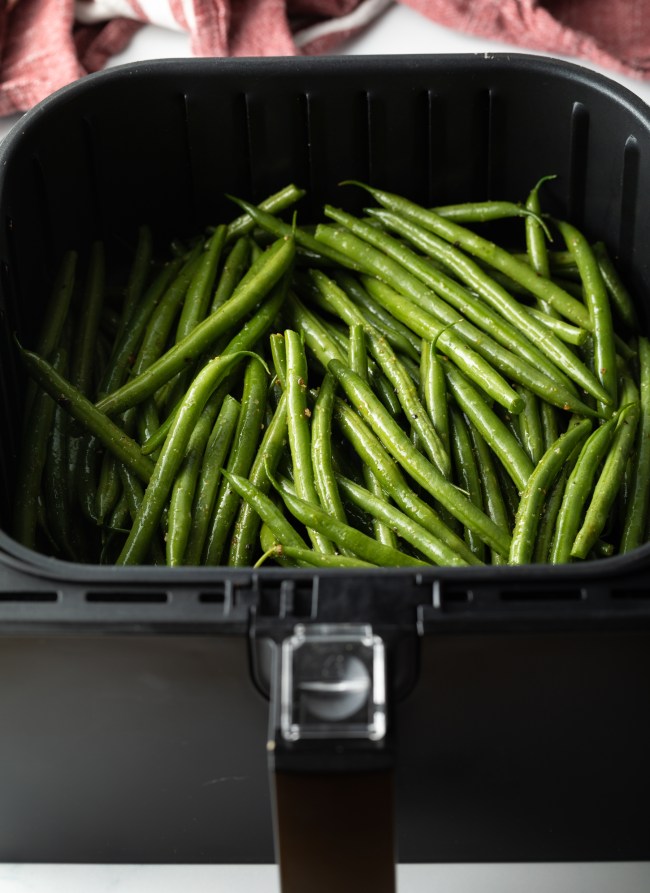 Long green beans in an air fryer basket.