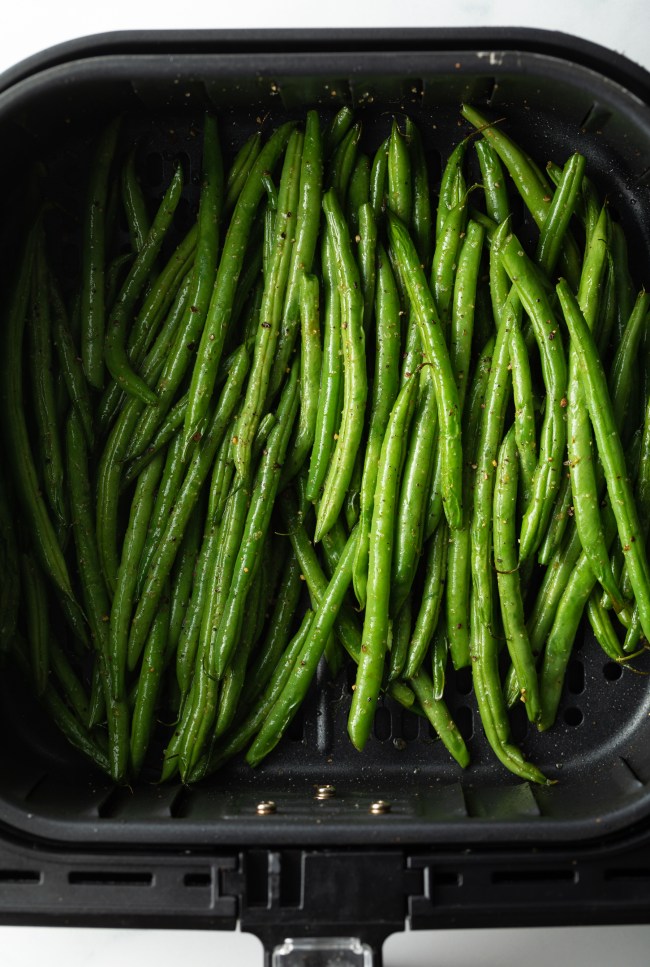 Long greenbeans in an air fryer basket.