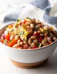 White bowl brimming with white bean and artichoke salad.