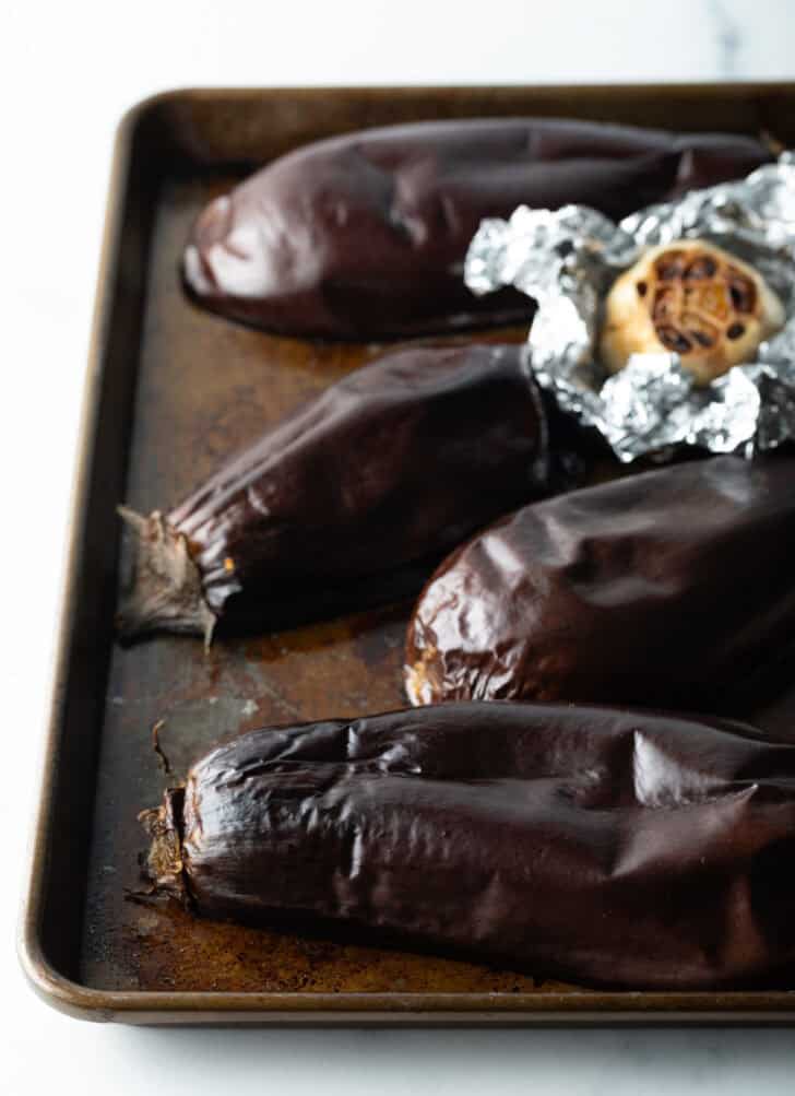 Roasted eggplant halves on a baking sheet.