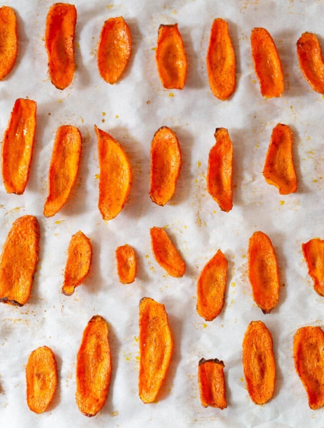 Carrot chips lined up on a baking sheet after being baked. 