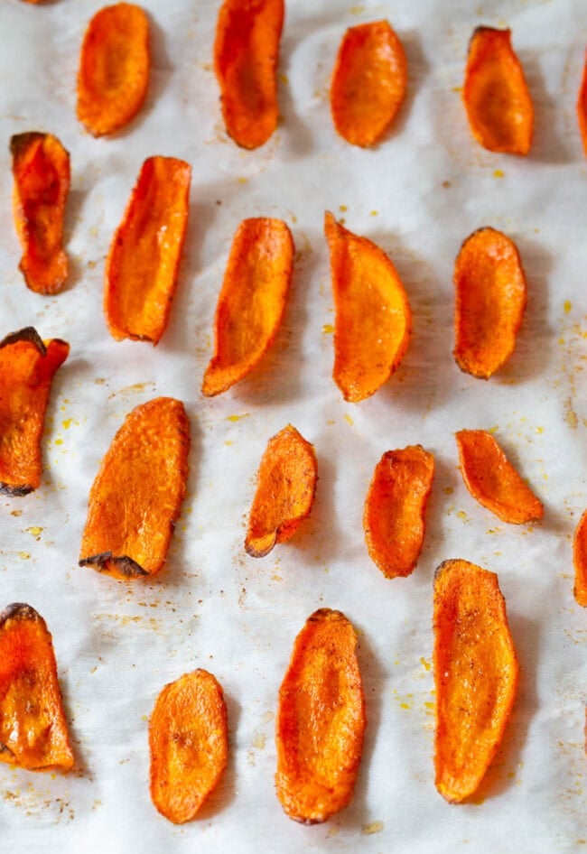 Carrot chips on a baking sheet lined with parchment after being baked. 