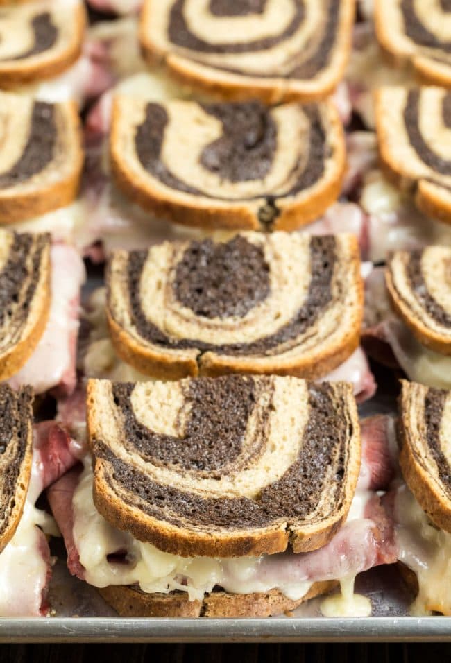 Oven Baked Reuben Sandwiches lined up on a sheet pan. 