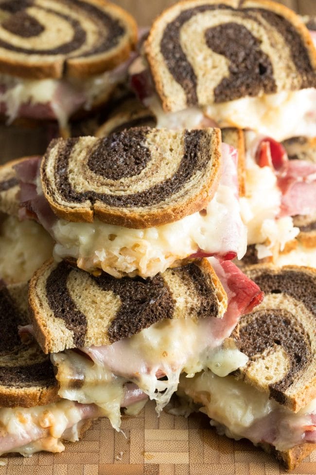 Baked Reuben sandwich recipe stacked on top of each other on a wooden background. 