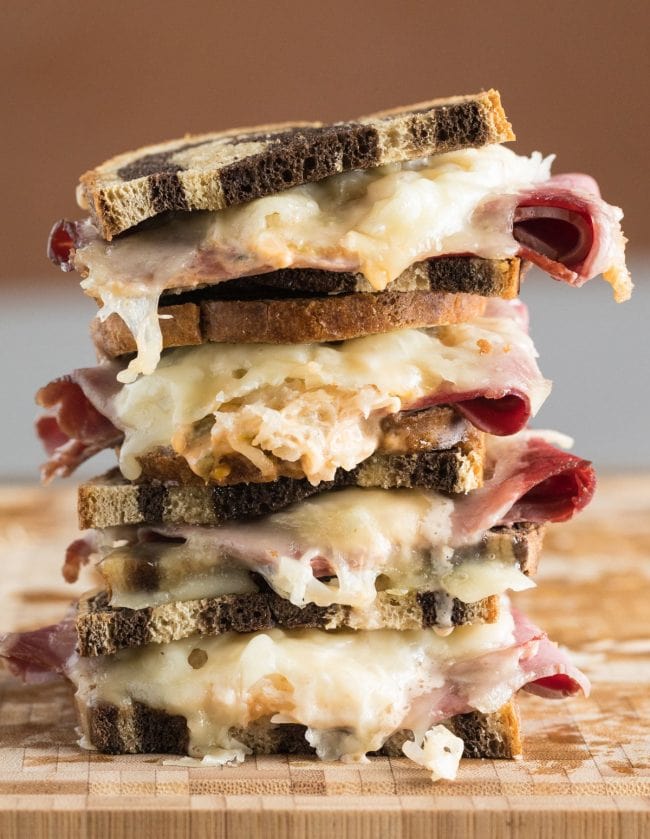 Reuben sandwiches stacked on top of each other. 