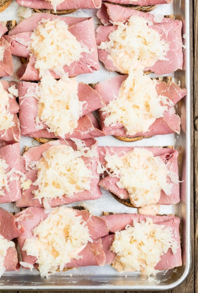 Bread topped with corned beef and sauerkraut on a sheet pan. 