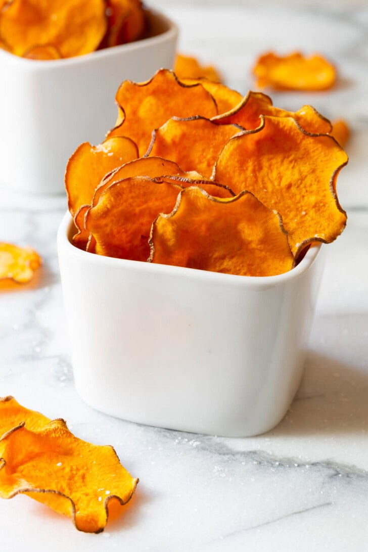 Sweet potato chips in a small white bowl to serve. 