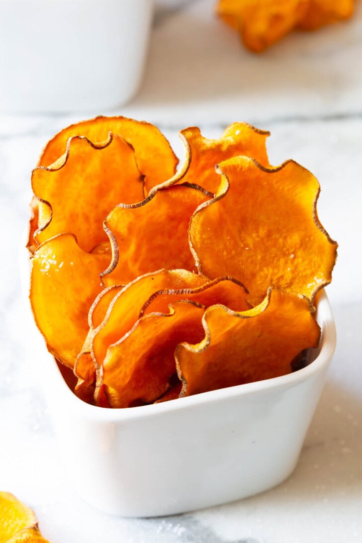 Delicious and healthy snack of sweet potato chips in a white container. 