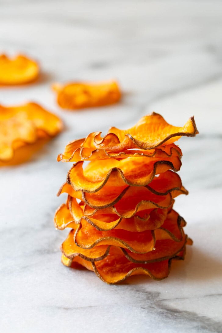 Baked sweet potato chips stacked up on top of each other. 