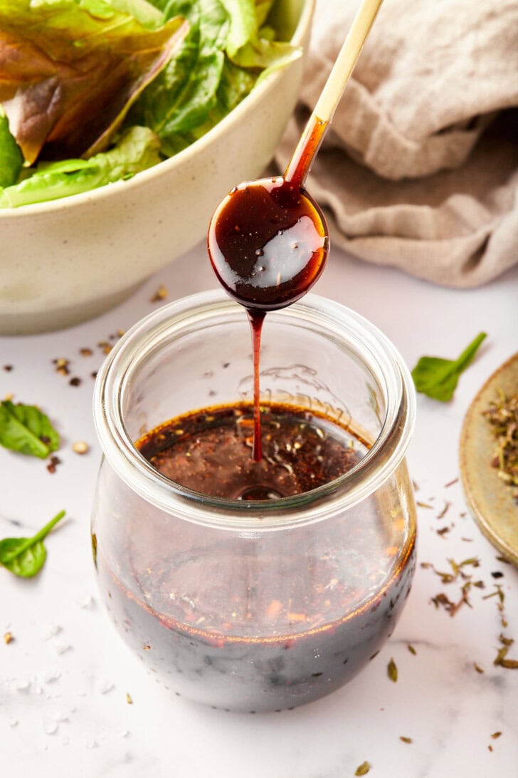 Spoon drizzling the dressing over the top of the jar to show consistency. 