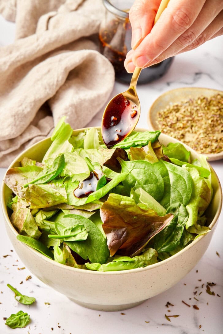 Homemade salad dressing with balsamic vinegar poured over greens.