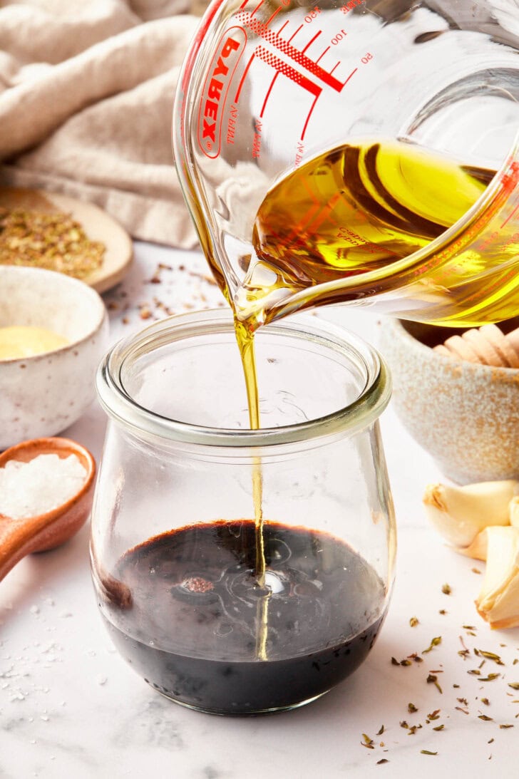 Balsamic vinaigrette recipe in jar with oil being added.