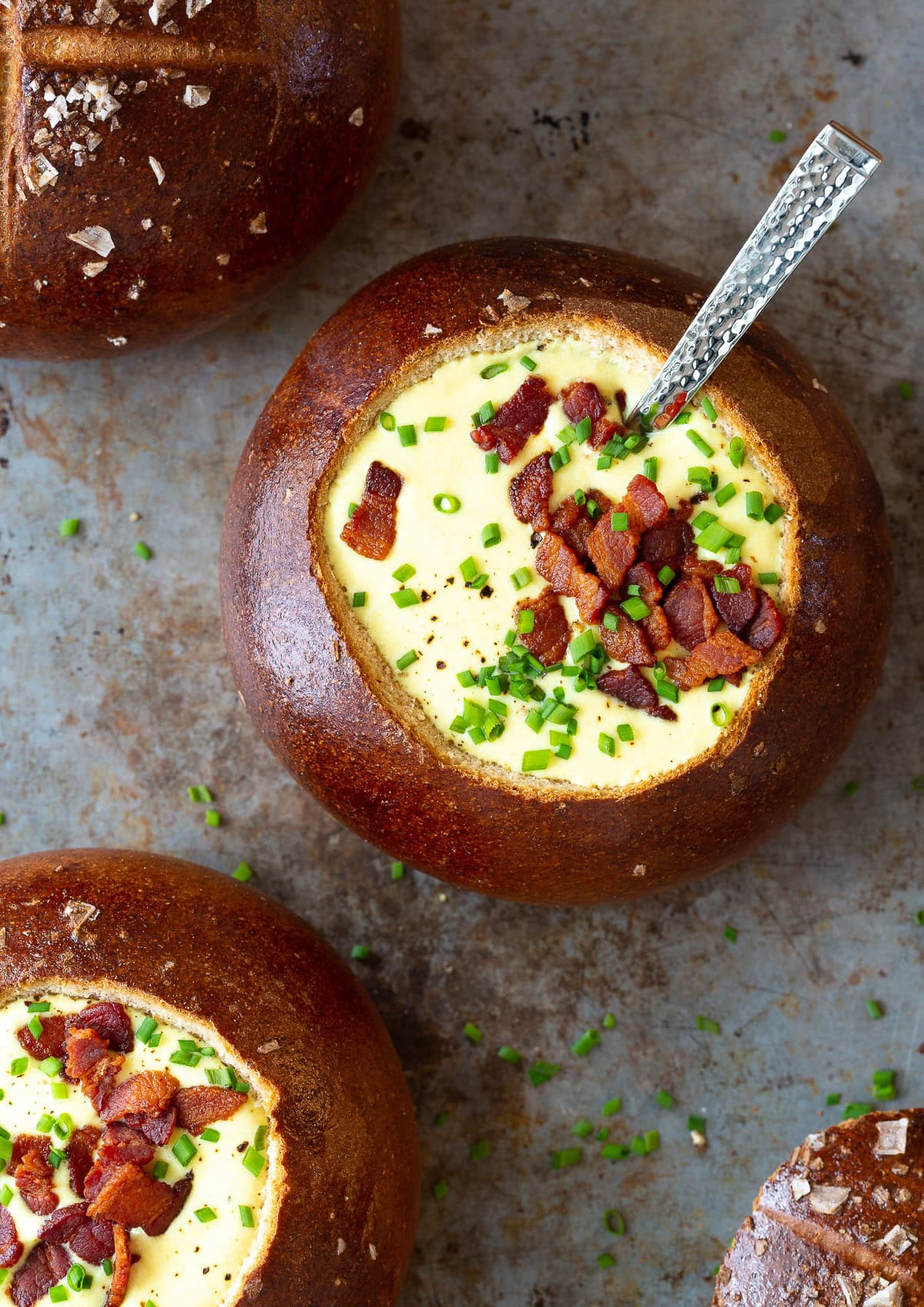 Overhead shot of bread bowl with beer cheese soup in it and bacon on top. 