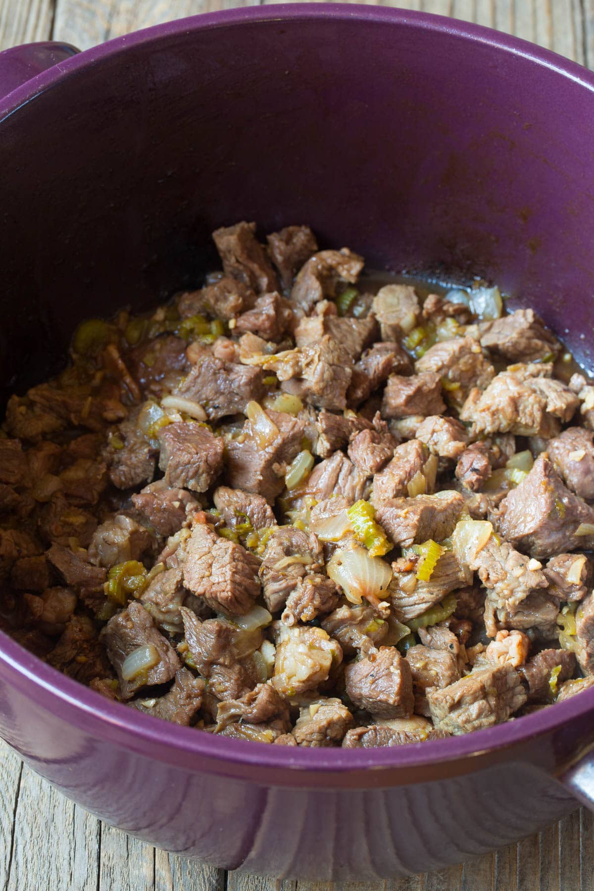 Beef and onions in a stock pot being seared. 