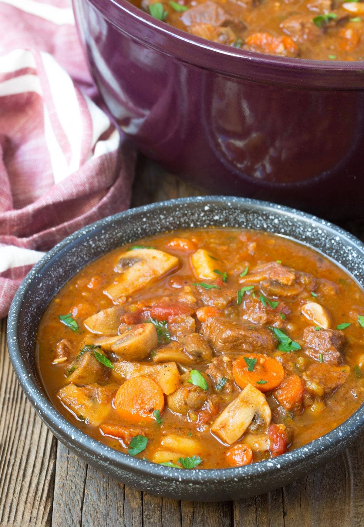 Bowl of beef stew topped with fresh parsley. 