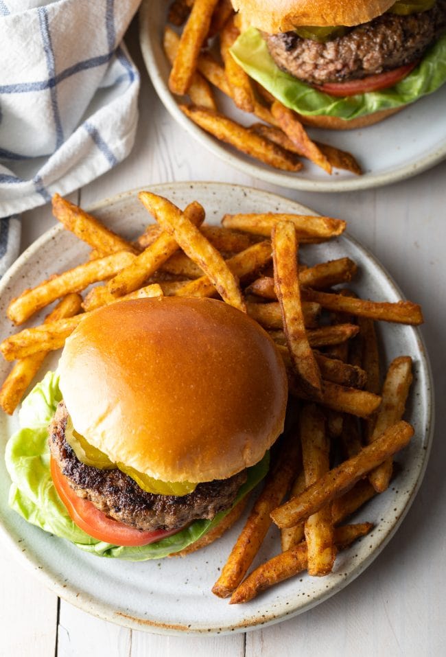 Overhead shot of hamburgers served on plates with french fries. 