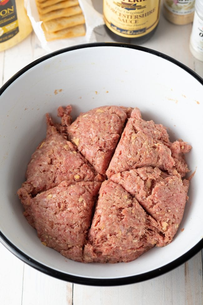 Ground beef mixed with other ingredients in a mixing bowl. 