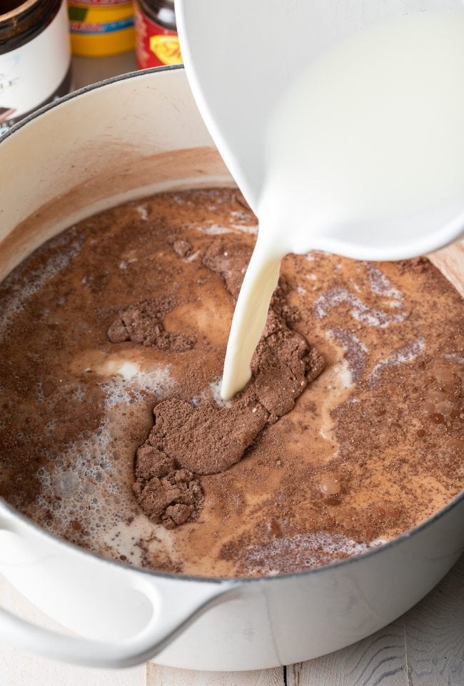 Milk being poured into the pot with the dry ingredients. 