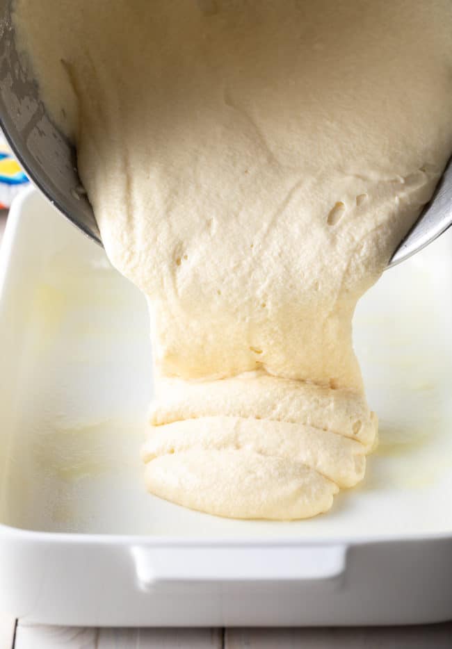 Cake batter being poured into a prepared baking dish.