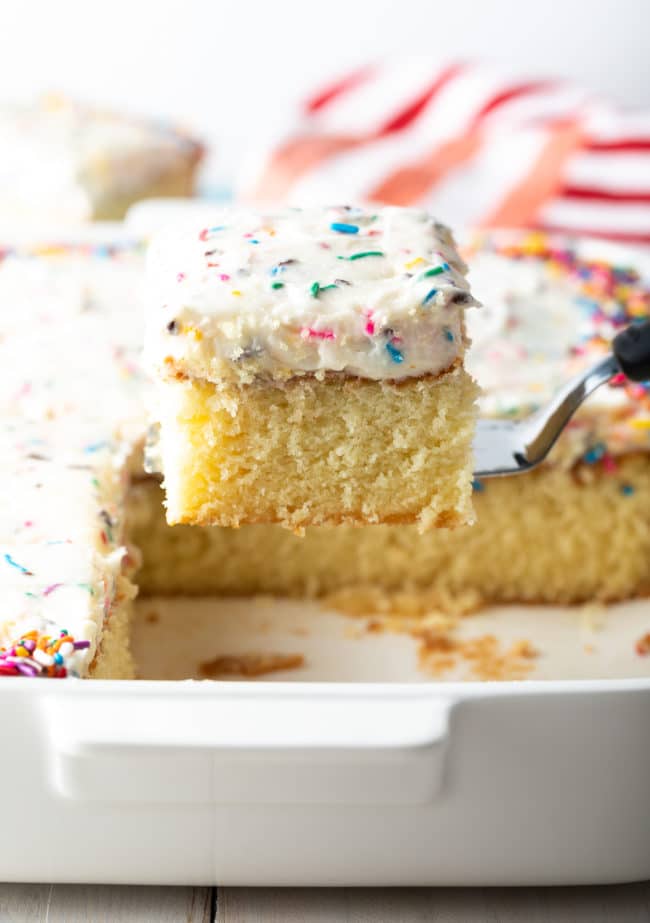 Spatula lifting a piece of birthday cake our of the baking dish of cake. 