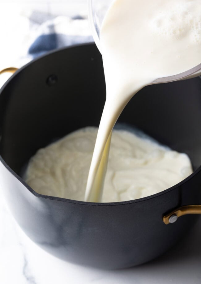 Pouring milk into large cooking pot.