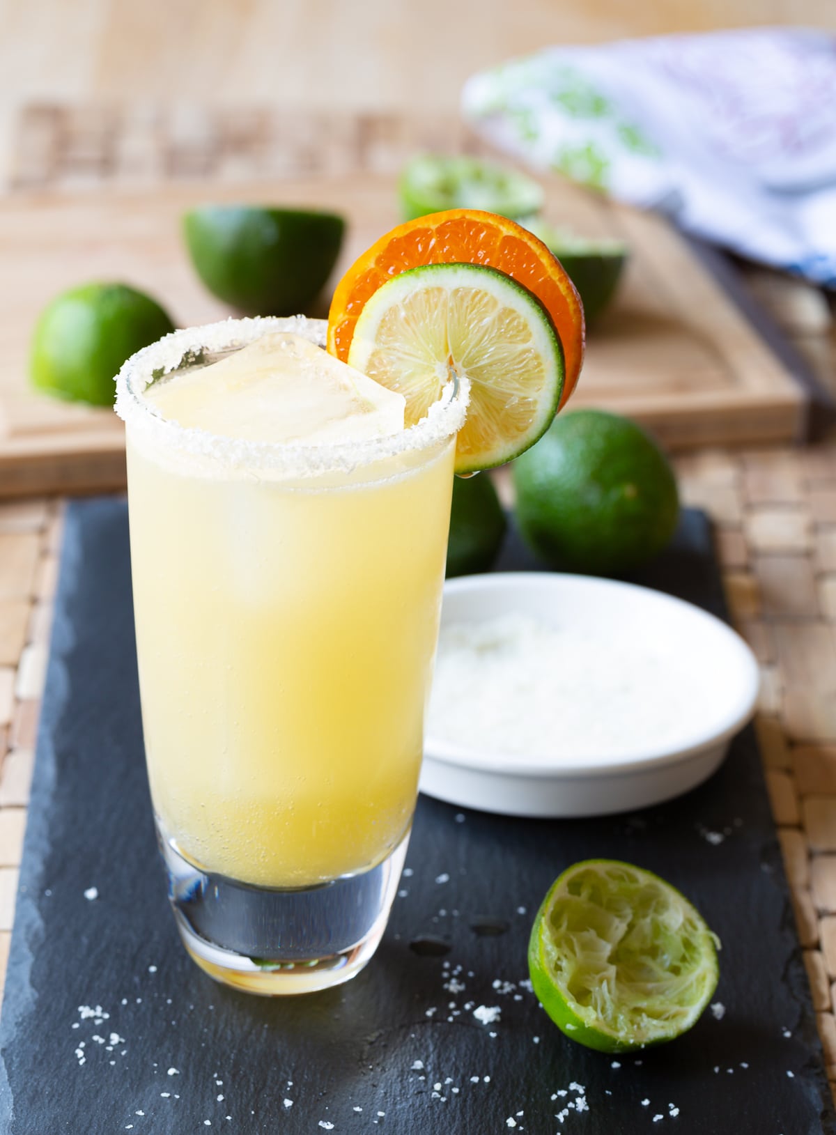 Margarita served in a glass with salt on the rim and citrus garnishes. 