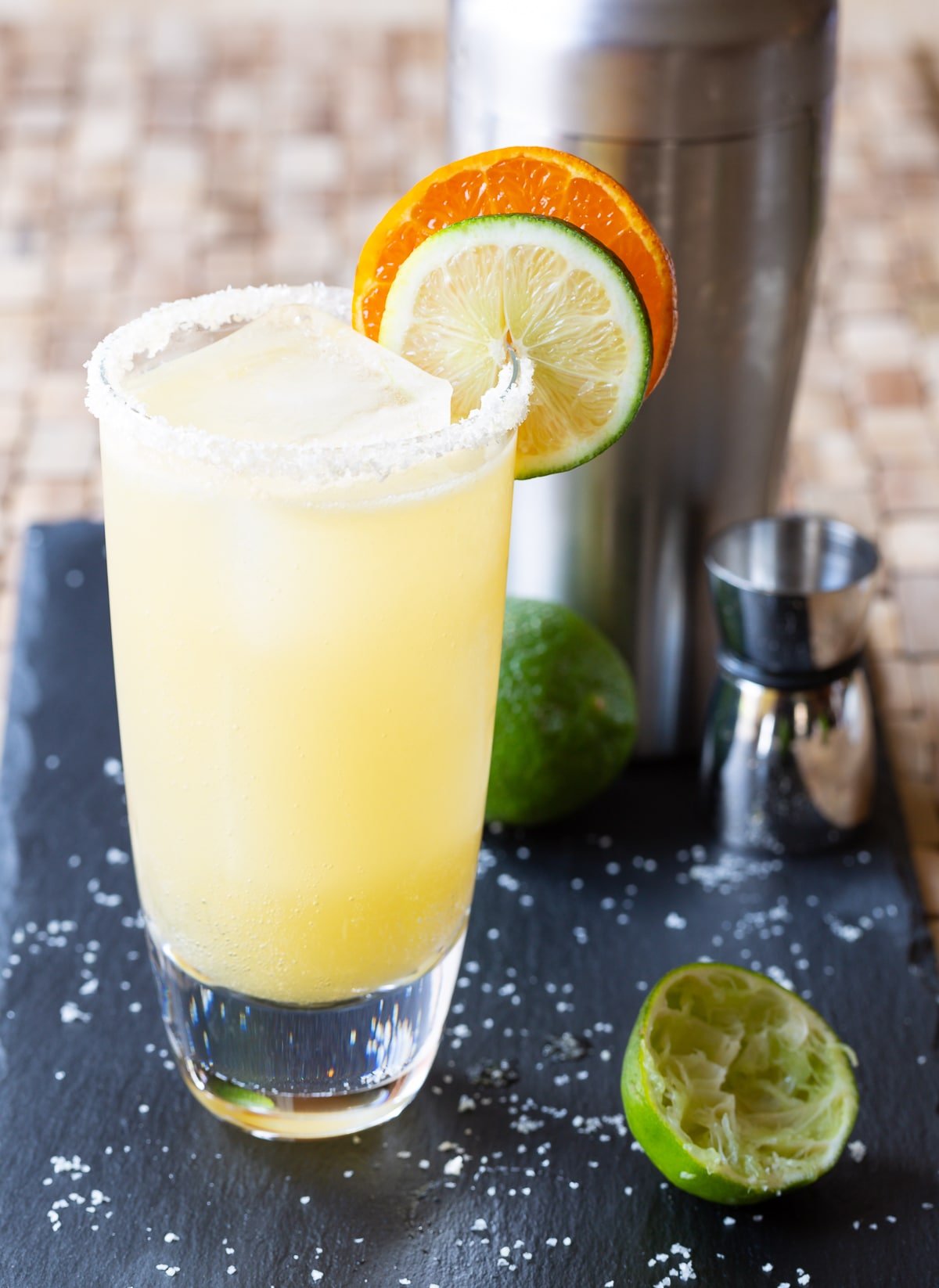 Margarita in a glass with salt on the rim and garnished with citrus slices. 