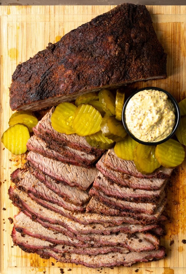 Dry Brine Brisket - slices of smoked beef brisket on a board with pickles and mustard