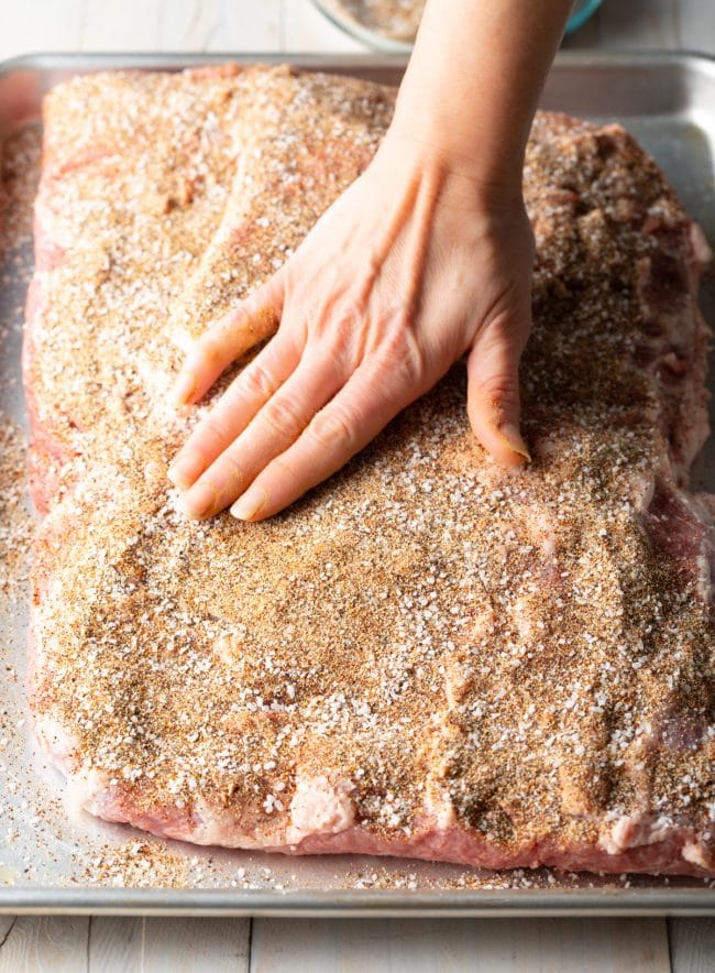 Hand rubbing the dry brisket brine spices onto the meat 