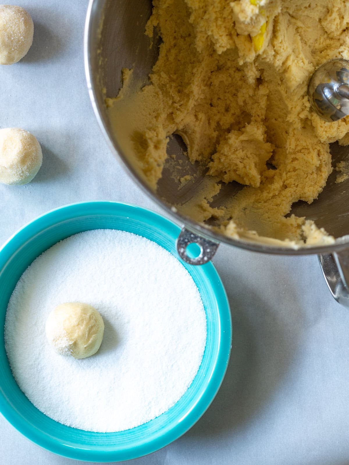 Small blue bowl with sugar and the dough being rolled in it
