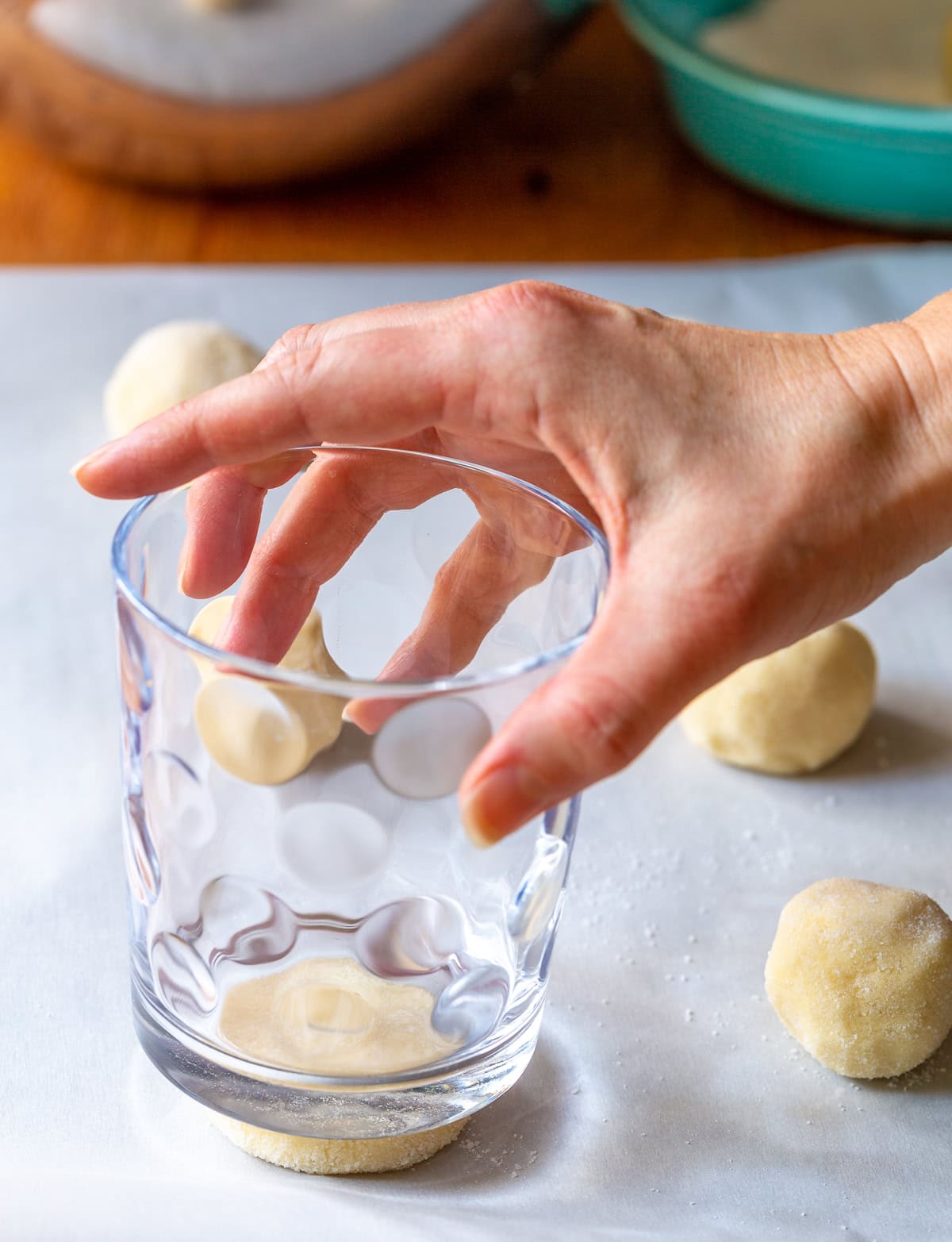 Rolled cookie dough being pressed with a glass cup to shape it
