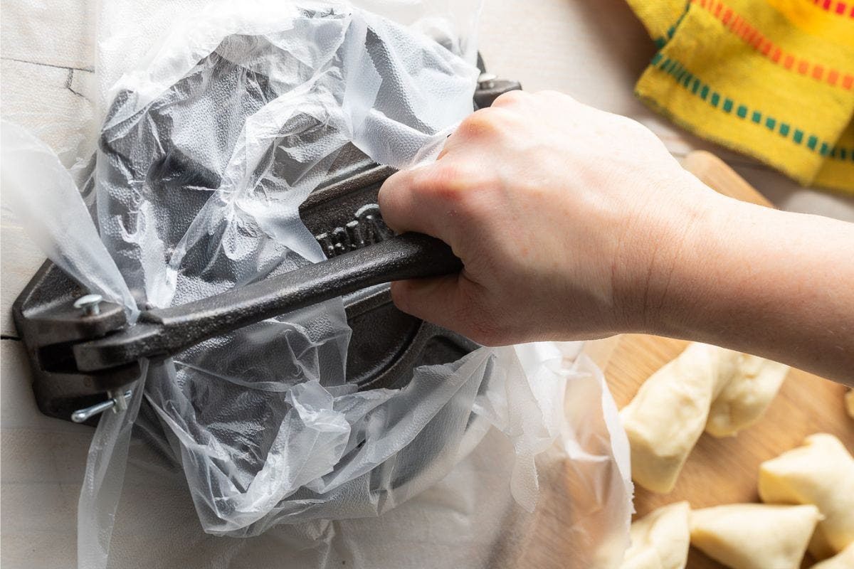 Hand pressing down a tortilla press. 