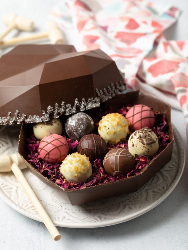 side viewing showing open box of chocolate shell filled with truffles