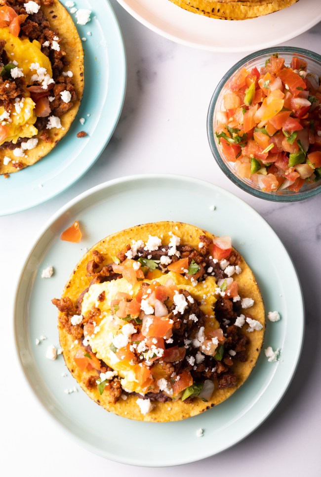 Loaded breakfast tostada on a plate, top down view.