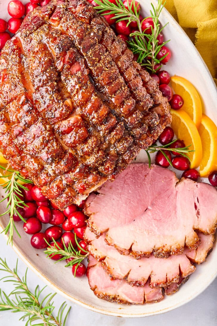 Brown Sugar Thanksgiving Ham sliced on platter with garnishes.