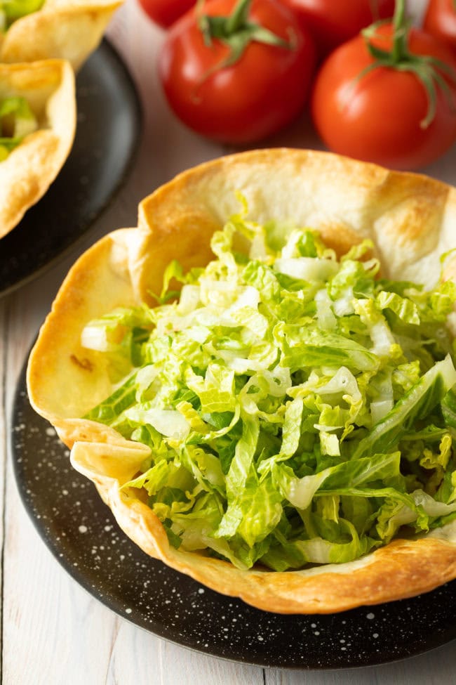 Taco bowl shell with shredded lettuce inside. 