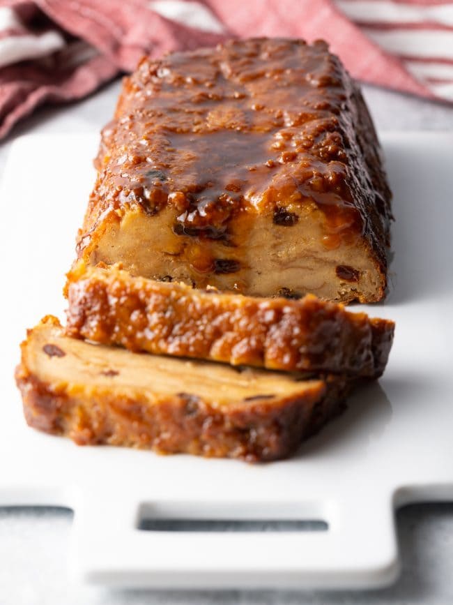 Finished bread pudding loaf pudding on a white cutting board with two slices.