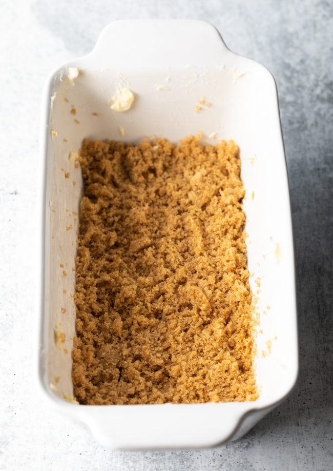 White loaf pan top view with layer of brown sugar at the bottom.