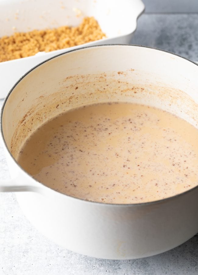 Side view of white cooking pan with milk and spices.