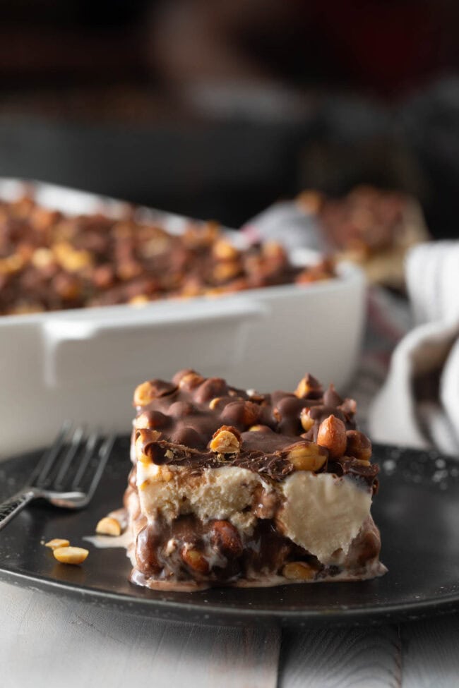 Slice of buster bar ice cream cake served on a black plate. 