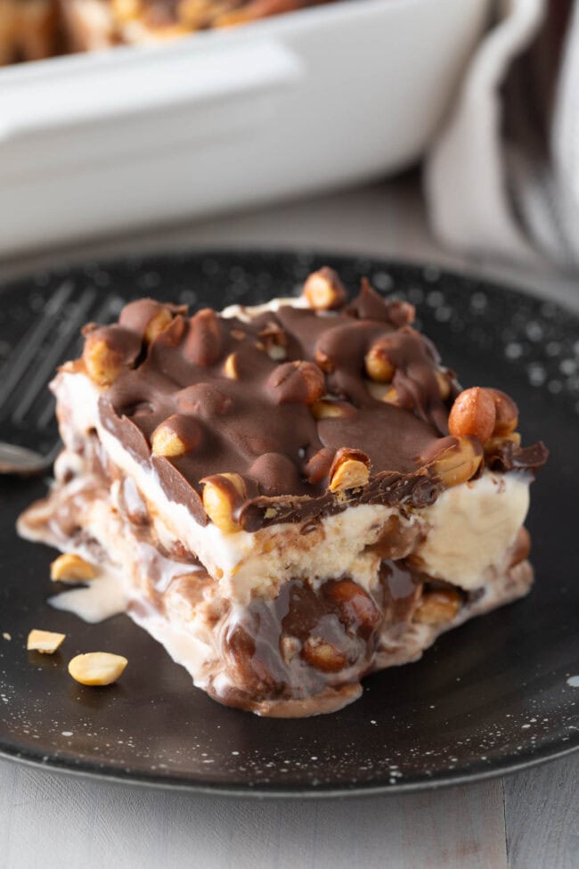 Slice of ice cream cake with some fudge oozing out. 