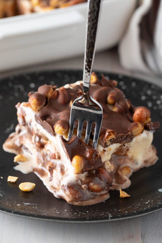 Buster bar ice cream cake cut on plate with fork sinking into the piece.