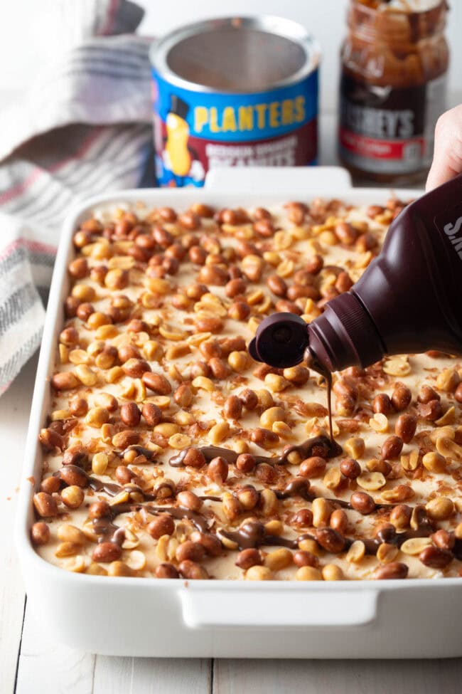 Hand pouring the chocolate magic shell layer on top of the buster bar cake. 