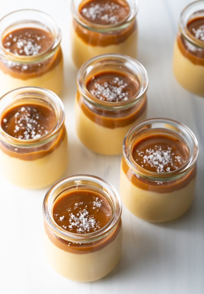 Italian Dessert Recipes - top side view several glass jars with homemade butterscotch budino topped with caramel and salt