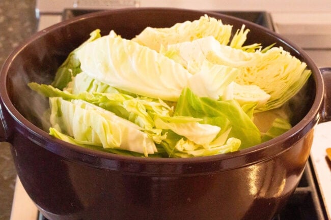 Cabbage cooking in a large pot on the stove. 