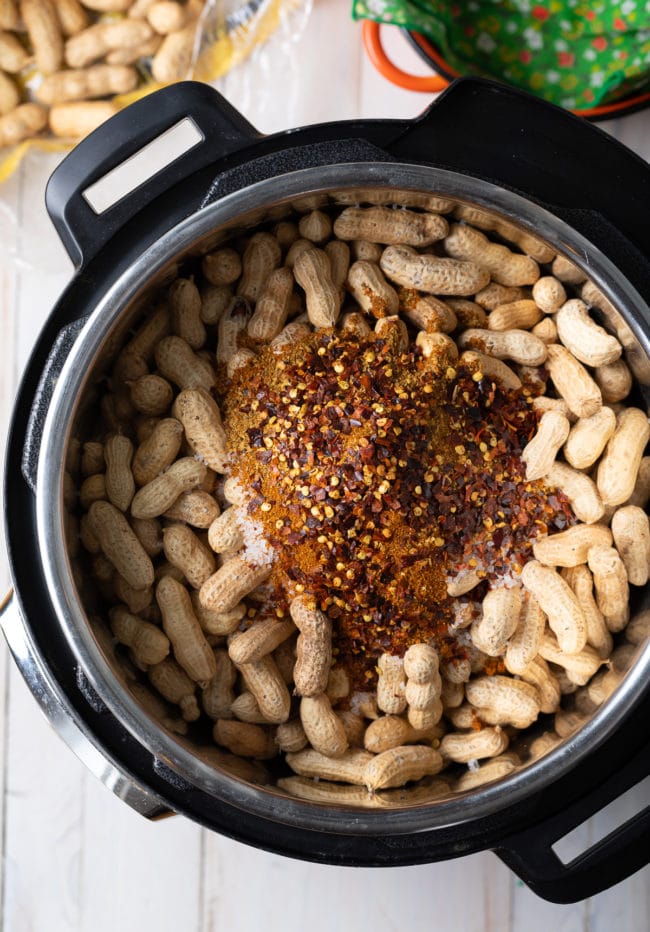 Peanuts in an Instant pot with spices piled on top. 